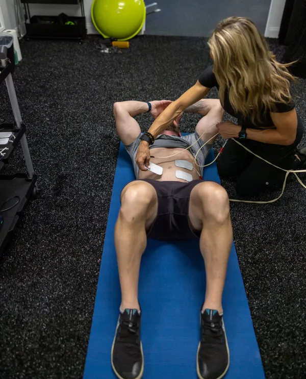 Chris doing core training with NXPro pads while Jess applies the device
